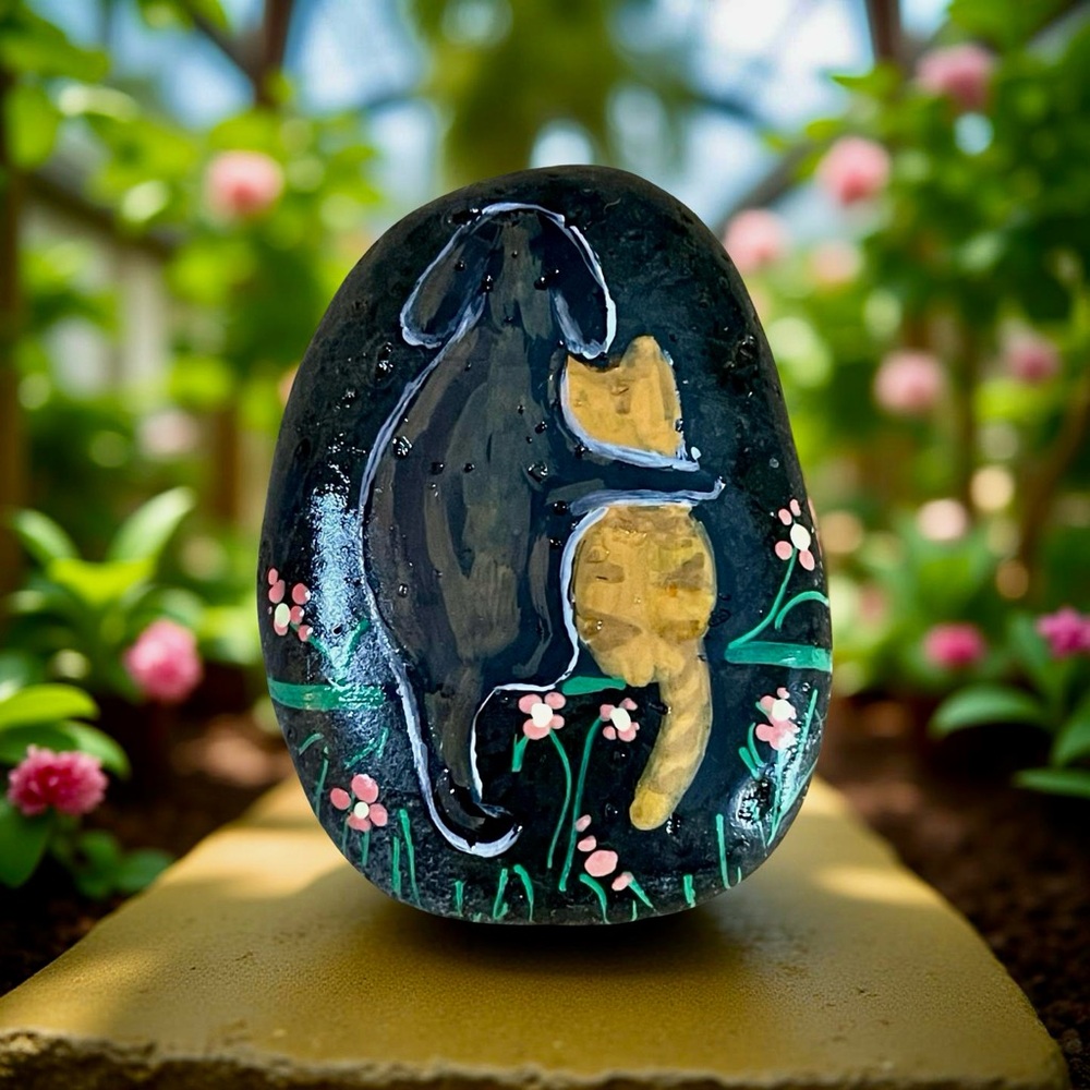 Hand crafted painted rock brown dog hugging orange cat on black stone flowers